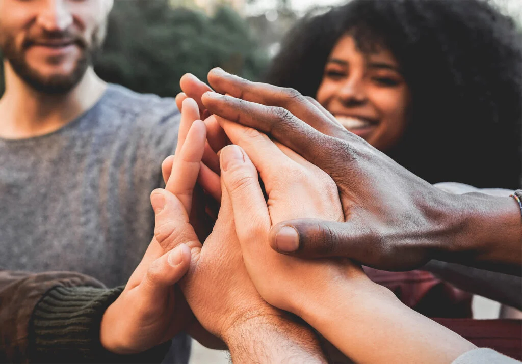 Young adults stacking their hands together