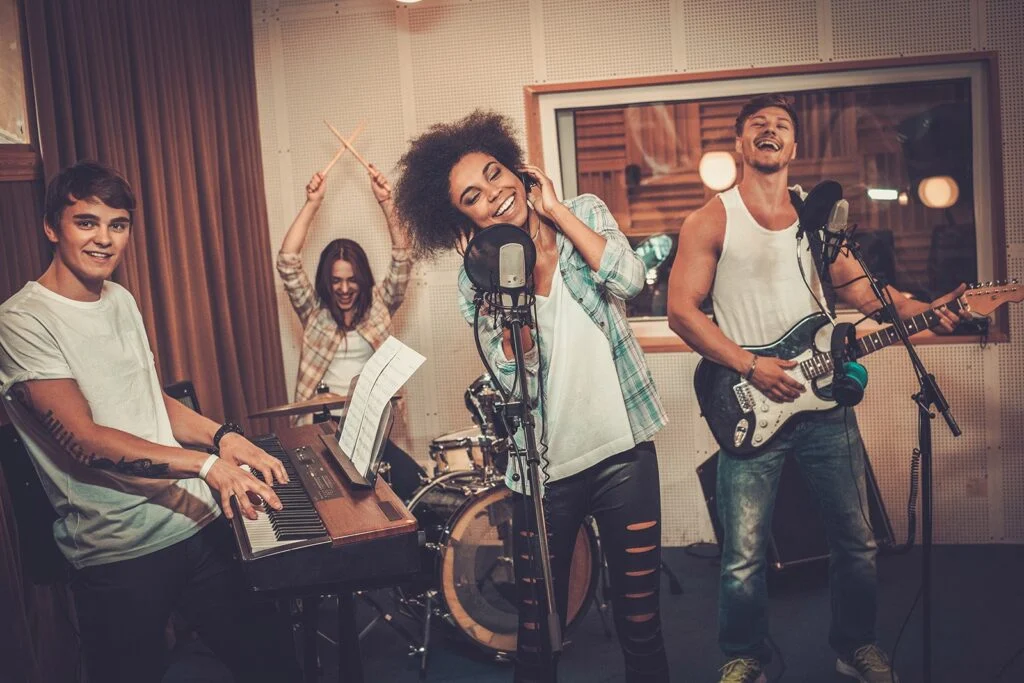 Student musicians playing and singing together in a practice room